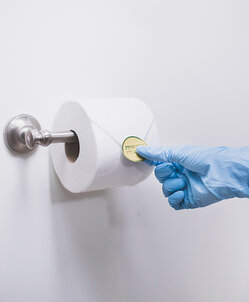 Professional maid folding toilet paper ends during bathroom cleaning services